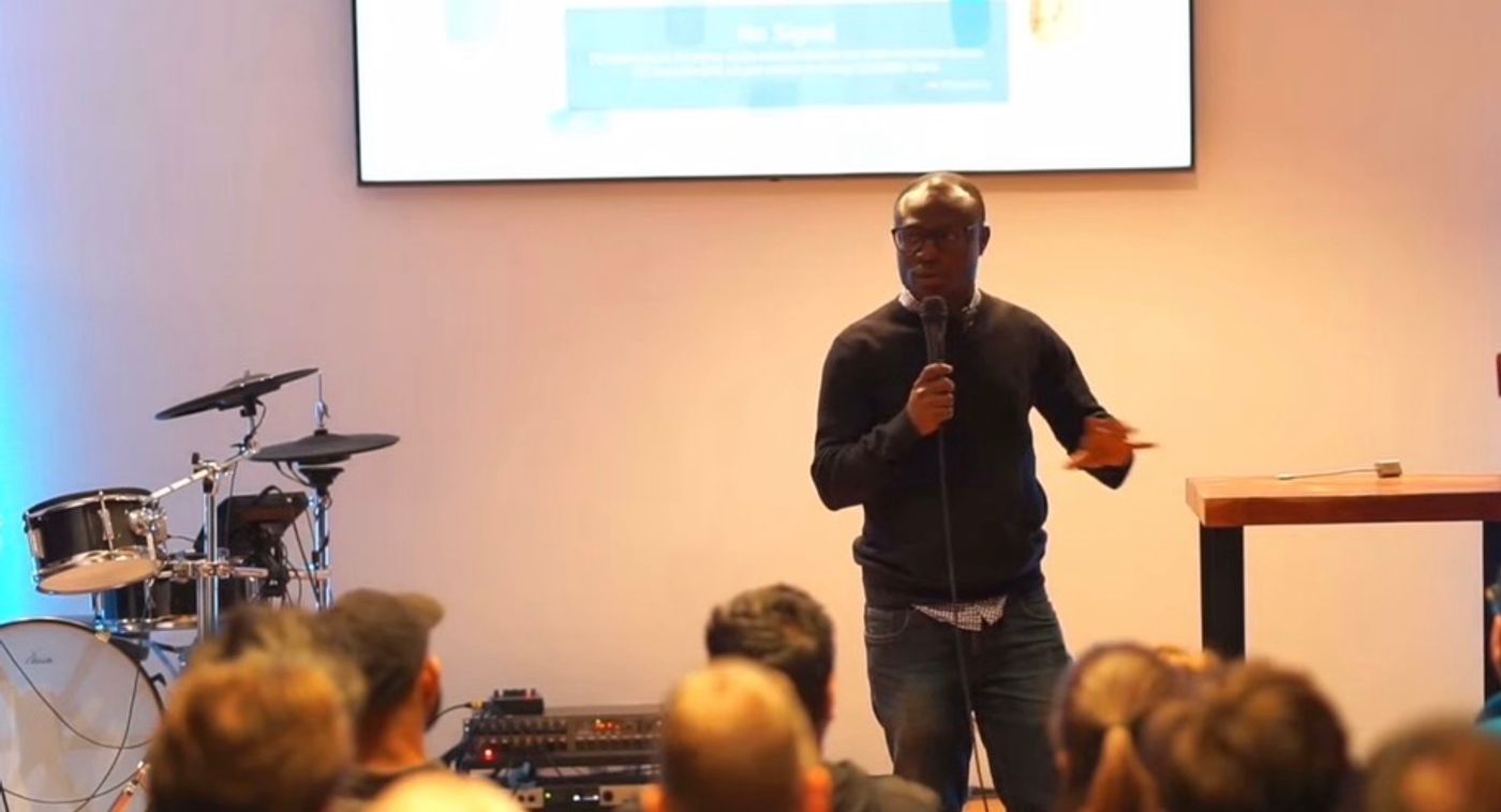 Dr. Rueben Okine speaking into a microphone at a public event
